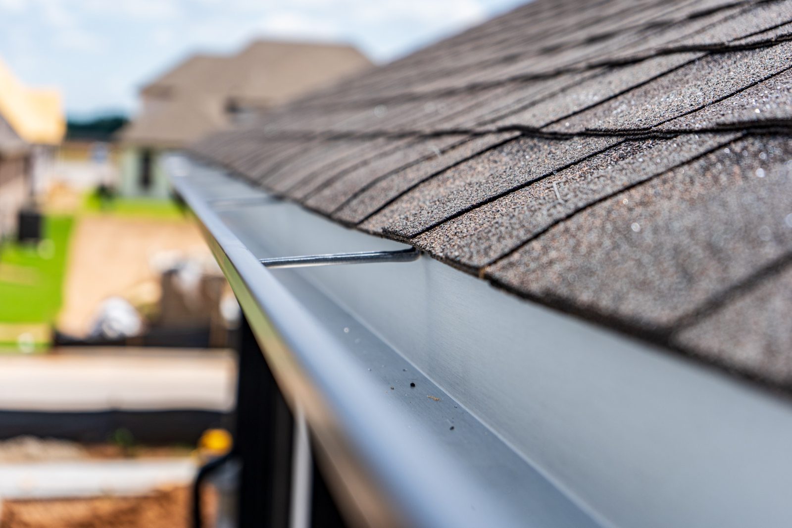 Close-up of a seamless gutter installed along a shingle roofline